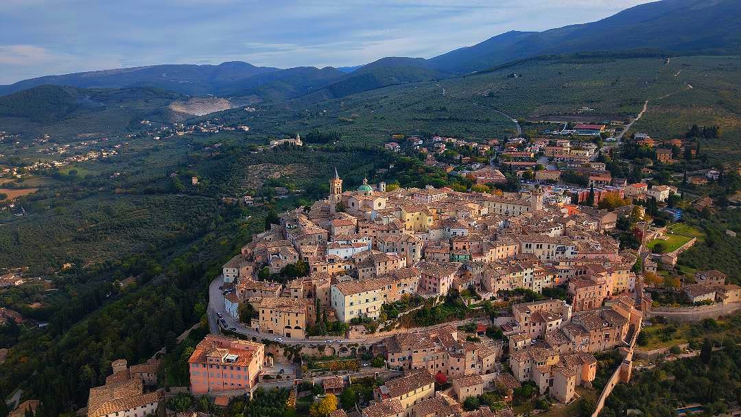 Una veduta aerea di Trevi rivela la sua affascinante forma a spirale, adagiata armoniosamente sulle curve di livello del colle, come una chiocciola che si avvolge su se stessa.